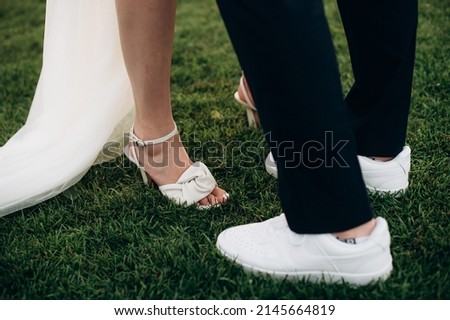 newlyweds stand on the grass, legs close-up