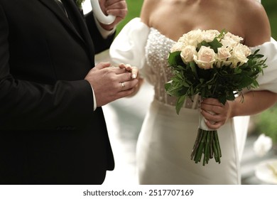 The newlyweds with wedding rings on their fingers hold hands and a bouquet of flowers - Powered by Shutterstock