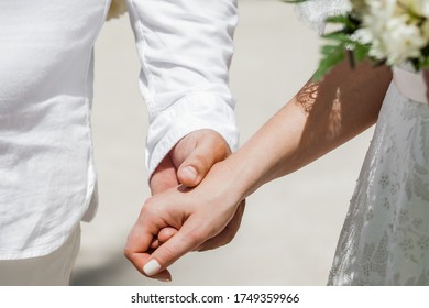 Newlyweds At The Wedding Romantic Couple Holding Hands During Destination Wedding Marriage Matrimonial Ceremony On The Sandy Beach In Dominican Republic, Punta Cana. Family, Love, Unity Concept.  