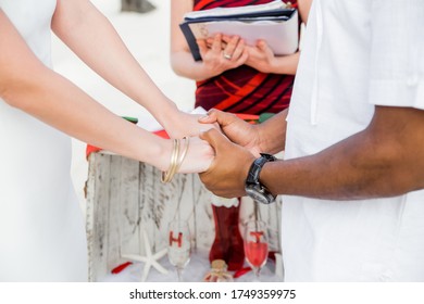 Newlyweds At The Wedding Romantic Couple Holding Hands During Destination Wedding Marriage Matrimonial Ceremony On The Sandy Beach In Dominican Republic, Punta Cana. Family, Love, Unity Concept.  