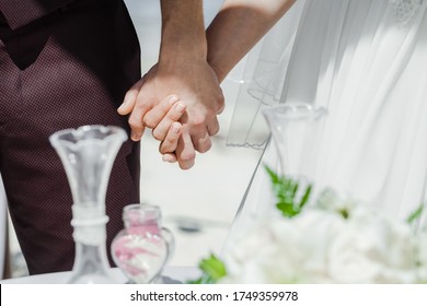 Newlyweds At The Wedding Romantic Couple Holding Hands During Destination Wedding Marriage Matrimonial Ceremony On The Sandy Beach In Dominican Republic, Punta Cana. Family, Love, Unity Concept.  