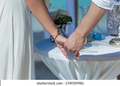 Newlyweds At The Wedding Romantic Couple Holding Hands During Destination Wedding Marriage Matrimonial Ceremony On The Sandy Beach In Dominican Republic, Punta Cana. Family, Love, Unity Concept.  