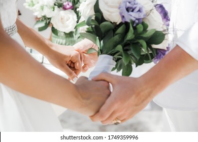 Newlyweds At The Wedding Romantic Couple Holding Hands During Destination Wedding Marriage Matrimonial Ceremony On The Sandy Beach In Dominican Republic, Punta Cana. Family, Love, Unity Concept.  