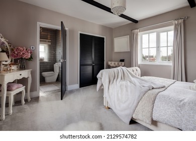 Newmarket, Suffolk - March 11 2019:  Stylish Luxury Bedroom Dressed With  Furniture And Soft Furnishings Including Faux Fur Bedspread, Dressing Table And Door Open To Washroom And Powder Room