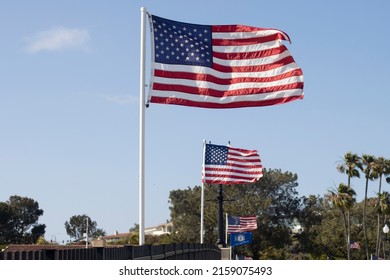 Newport Beach, CA, USA - May 8, 2022: Waving American flags in the wind against blue sky on the Balboa Island Channel Bridge in Newport Beach, California.