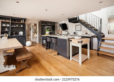 Newport, Essex - July 10 2018: Ultra modern fashionable chic kitchen with breakfast bar and dining table decorated and finished in shade of whites, grey and black