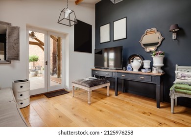 Newport, Essex - July 10 2018: Fashional modern hall or study in home with contrasting dark grey and white walls, exposed timber flooring and computer television monitor on sidetable.