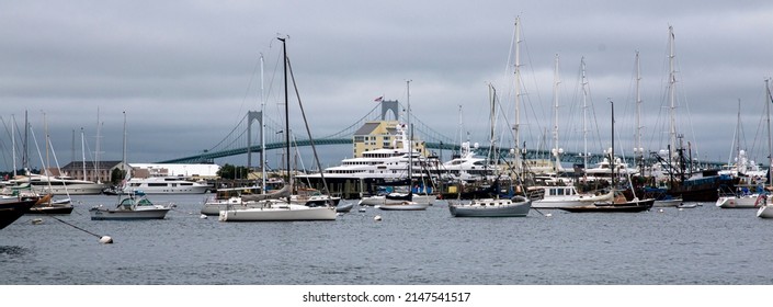 Newport, Rhode Island, USA - 2 July 2021: Newport harbor with many moored sailboats and yachts with the newport bridge in the background on a cloudy rainy summer day.