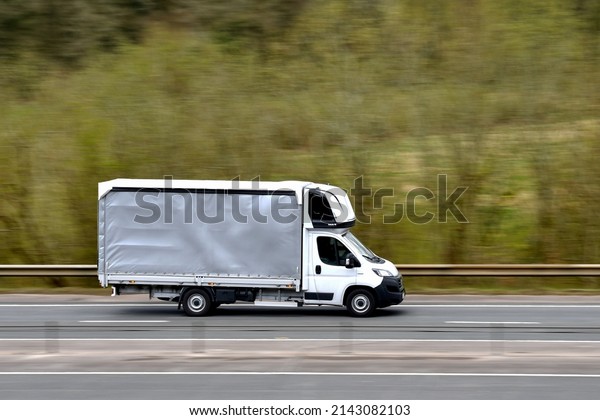 Newport, Wales - March 2022: Light goods vehicle\
box van driving on a dual carriageway, with slow shutter used to\
blur motion.