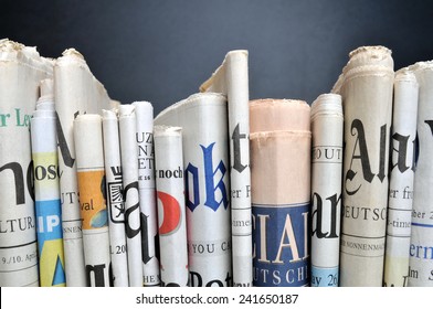 News - Folded newspapers in front of black wall - Shutterstock ID 241650187
