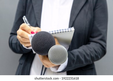 News Reporter Or TV Journalist At Press Conference Or Media Event, Holding Microphone And Writing Notes. Broadcast Journalism Concept.