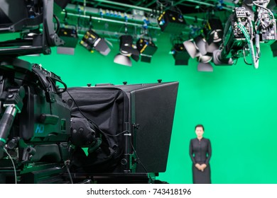 Newscaster Or Announcer Working In Broadcast Television Virtual Greenscreen Studio And Looking At Camera.Also Has LED Lights On The Ceiling.