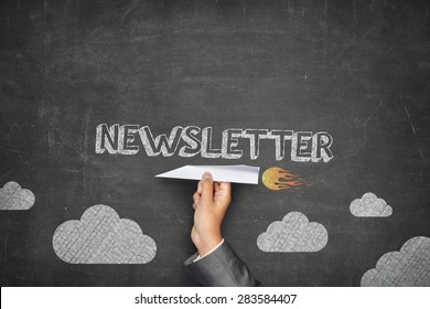 Newsletter concept on black blackboard with businessman hand holding paper plane - Shutterstock ID 283584407