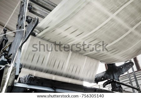 Newspaper being printed on rolls of paper