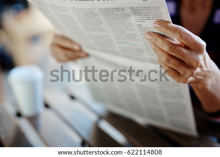 Newspaper broadsheet held and read by senior female