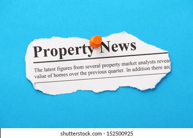 Newspaper Clipping For Property News Pinned To A Blue Paper Background