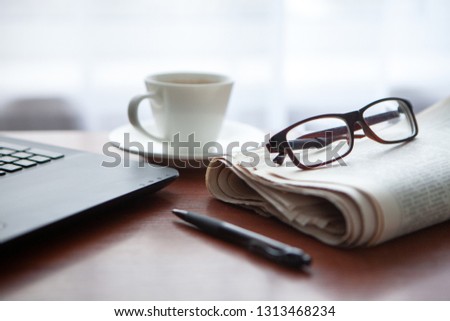 Newspaper with computer on table. Coffee break.