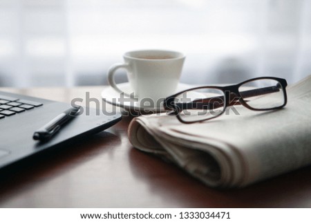 Newspaper with computer on table. Coffee break.