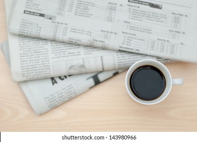 A Newspaper And A Cup Of Coffee On A Wooden Table