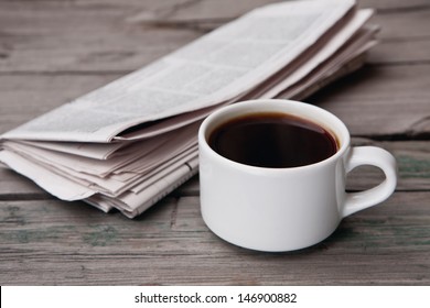 A Newspaper And A Cup Of Coffee On A Wooden Table 