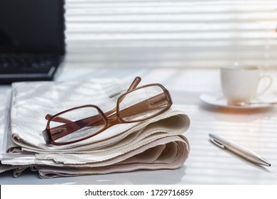 Newspaper And Glasses Over Office Desk