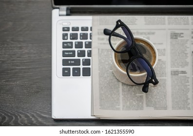 Newspaper, Laptop, Glasses And Cup Of Coffee On Wooden Table Background. Empty Copy Space For Inscrption. 