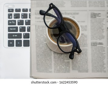 Newspaper, Laptop, Glasses And Cup Of Coffee On Wooden Table Background. Empty Copy Space For Inscrption. 