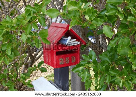 A newspaper left inside red timber mail box.