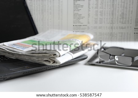 Newspaper on laptop with blurred newspaper background