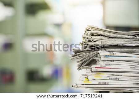 newspaper stack put on the table in library. Newspapers are always available with libraries.But the number of newspapers in the stack is decreasing.As people turn to read more data on the Internet.