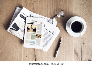 Newspaper with tablet on wooden table