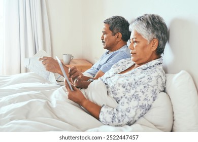 Newspaper, tablet and senior couple in bedroom, reading and relax with morning news. Retirement, pensioner and old with elderly woman, house and digital app with relationship, break and marriage - Powered by Shutterstock