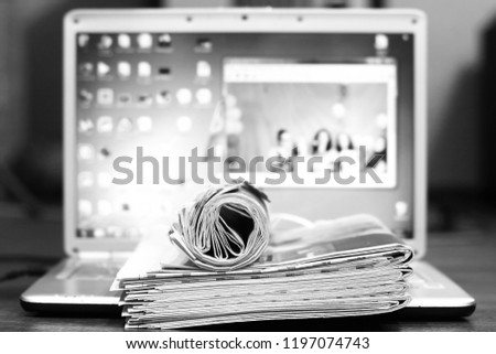 Newspapers and computer. Folded and rolled papers and magazines on keyboard of open laptop. Concept for news by different sources of information - screen of electronic device or paper pages of tabloid