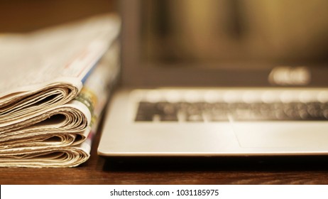 Newspapers and computer. Laptop and daily papers on the table. Fresh news by  paper or by electronic device, different ways of communication. Source of information, actual data on pages or on screen  - Shutterstock ID 1031185975