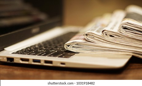 Newspapers and computer. Laptop and daily papers on the table. Fresh news by  paper or by electronic device, different ways of communication. Source of information, actual data on pages or on screen  - Shutterstock ID 1031918482
