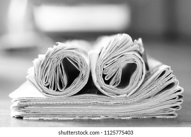 Newspapers (folded and rolled) stacked in pile, selective focus                               