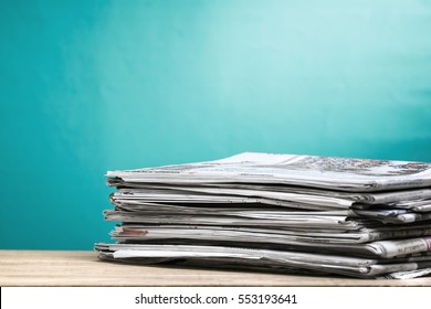 Newspapers folded and stacked on wooden board - Shutterstock ID 553193641