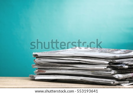 Newspapers folded and stacked on wooden board