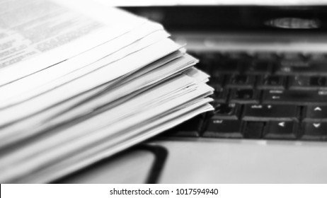Newspapers and laptop. Pile of daily papers with news on the computer. Pages with headlines, articles folded and stacked on keypad of electronic device. Modern gadget and old journals, focus on paper - Shutterstock ID 1017594940
