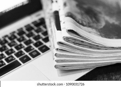 Newspapers and laptop. Pile of daily papers with news on the computer. Pages with headlines, articles folded and stacked on keypad of electronic device. Modern gadget and old journals, focus on paper - Shutterstock ID 1090031726