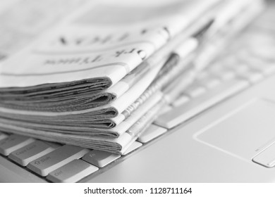 Newspapers and laptop. Pile of daily papers with news on the computer. Pages with headlines, articles folded and stacked on keypad of electronic device. Modern gadget and old journals, focus on paper  - Shutterstock ID 1128711164