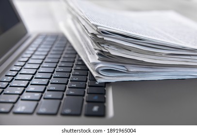 Newspapers and laptop. Pile of daily papers with news on the computer. - Shutterstock ID 1891965004