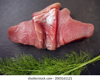 NEWTON Le WILLOWS. MERSEYSIDE. ENGLAND. 06-04-21.
A Raw Tuna Steak On A Black Slate Platter Against A Branch Of Fresh Dill.