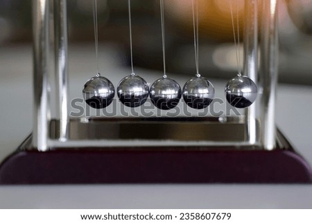 The Newton's cradle is a device that demonstrates the conservation of momentum and the conservation of energy with swinging spheres. Soft and selective focus.                               