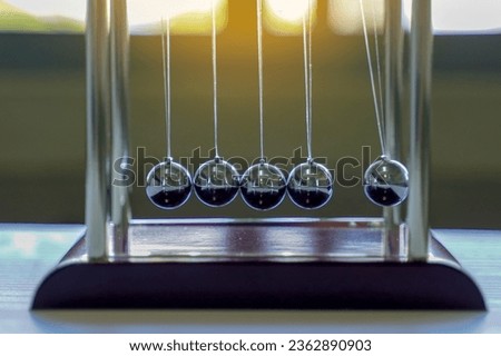 The Newton's cradle is a device that demonstrates the conservation of momentum and the conservation of energy with swinging spheres. Soft and selective focus.                               