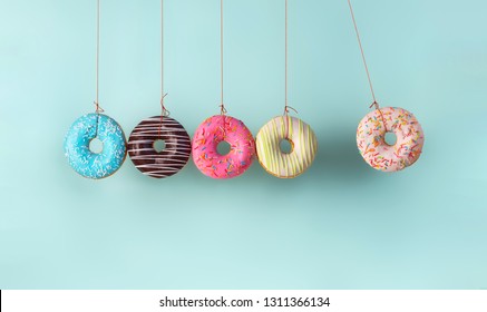 Newtons Wiege aus Donuts. Kollisionsbälle aus Donuts. Harm des Zuckers, spart Zeit oder gesunde Ernährung Konzept. Abhängigkeit von Aromen, Diabetes-Problemen, Gewichtsverlust.