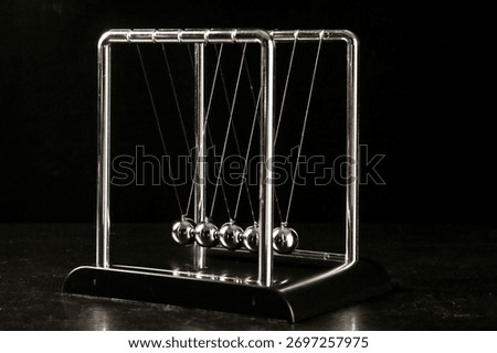 Newton's cradle pendulum demonstrating physics principles of momentum and energy transfer with suspended metal spheres on dark background