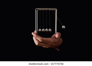 Newton's Pendulum Or Cradle In Human Hands On Dark Background