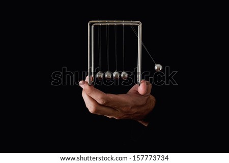 Newton's pendulum or cradle in human hands on dark background