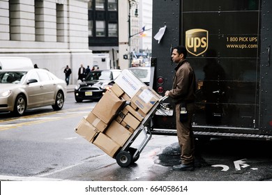 New-York - NOV 13: UPS delivery worker waiting by his truck to cross the street holding a cart full with packages in New-York, USA on November 13, 2012.